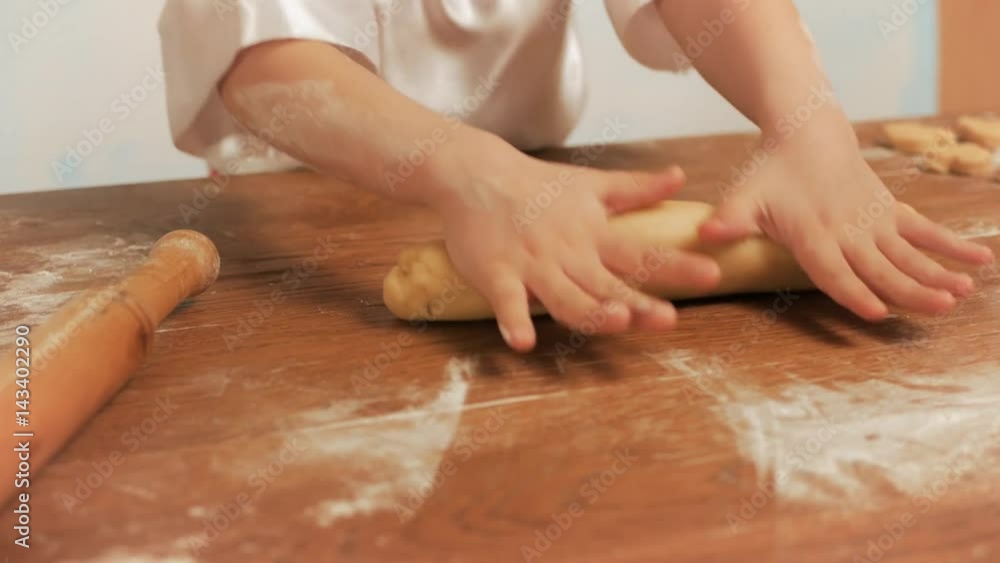 Girl chef rolls the dough by hand on a table, closeup. Girl chef rolls the dough by hand on a table, closeup.