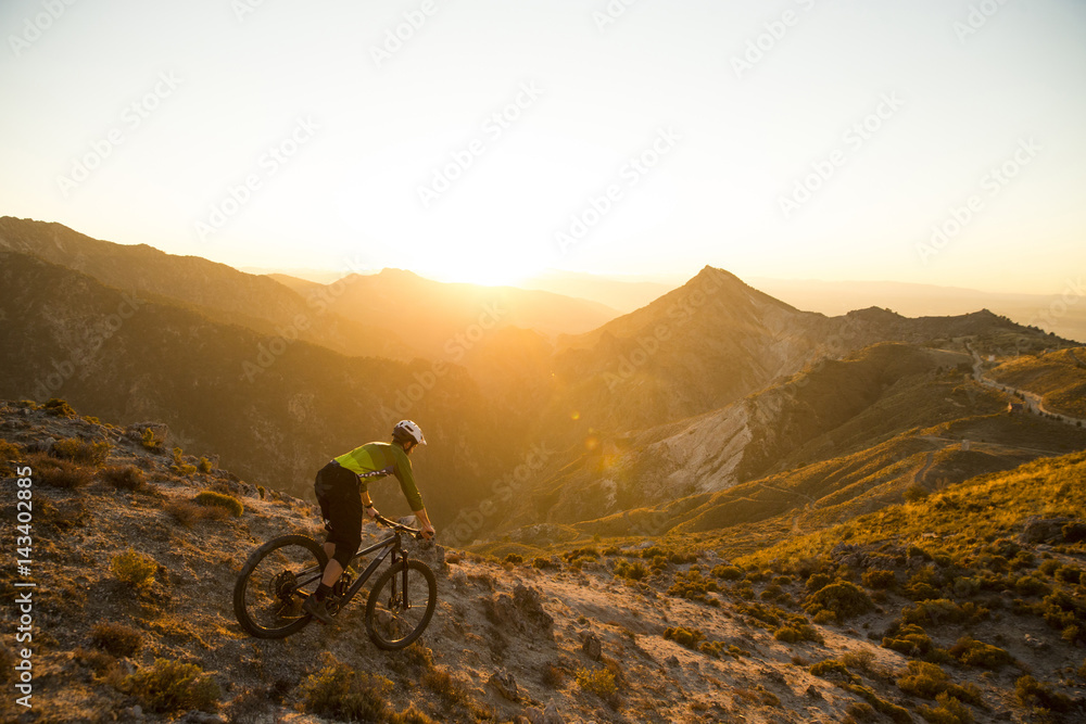 Naklejka premium Cyclist man riding mountain bike at sunset