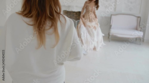 Gergeous woman in golden dress with ostrich feathers posing in studio. Photographer work with model. Backstage. photo