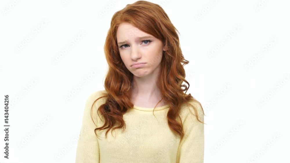 Sad disappointed young woman with long red hair showing thumbs down over white background Sad disappointed young woman with long red hair showing thumbs down over white background