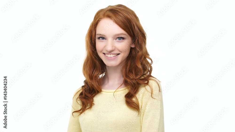 Smiling confident young woman with long red hair pointing two fingers at camera isolated over white background Smiling confident young woman with long red hair pointing two fingers at camera isolated over white background