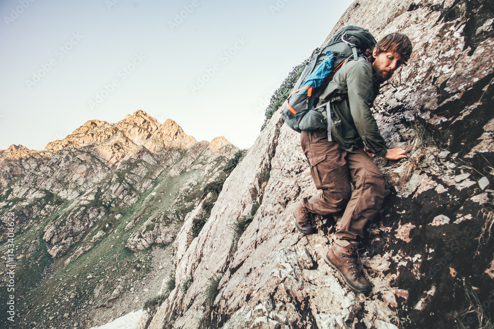 Climber Man climbing rocky mountains with backpack Travel Lifestyle concept adventure summer vacations outdoor mountaineering sport risk and endurance