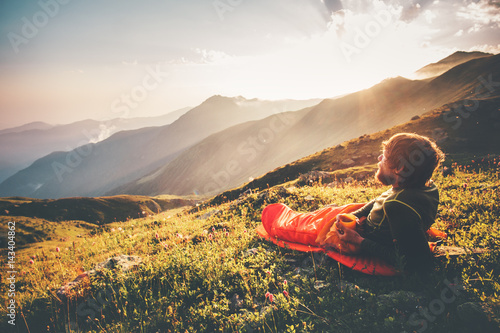 Man relaxing in sleeping bag enjoying sunset mountains landscape Travel Lifestyle camping concept adventure summer vacations outdoor hiking mountaineering harmony with nature photo