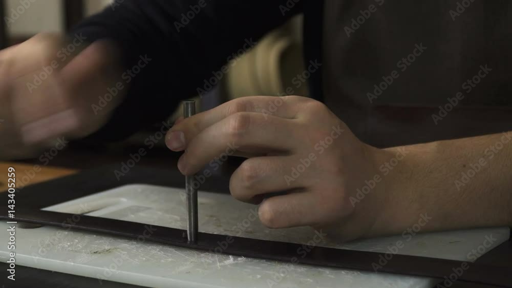Craftsman working with a piece of leather on the table. Making a leather product. 
