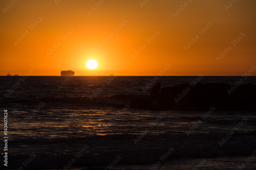 Sonnenuntergang am Strand von Kalifornien mit Frachtschiff