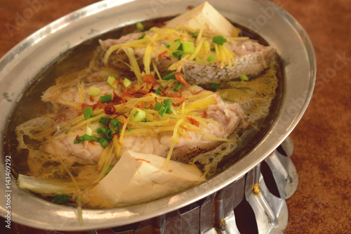 steamed grouper with ginger, tofu and chinese soy sauce served on hot pot.
