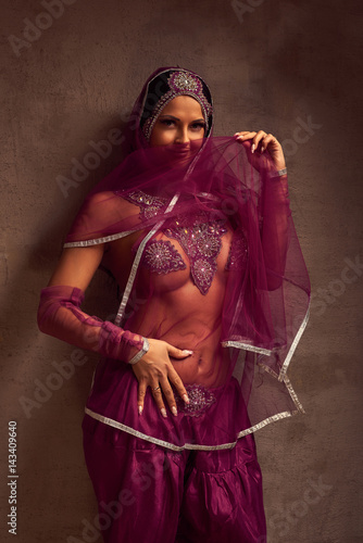 Eastern beautiful brunette .belly-dancer woman in afghani pants, purdah and adornment.