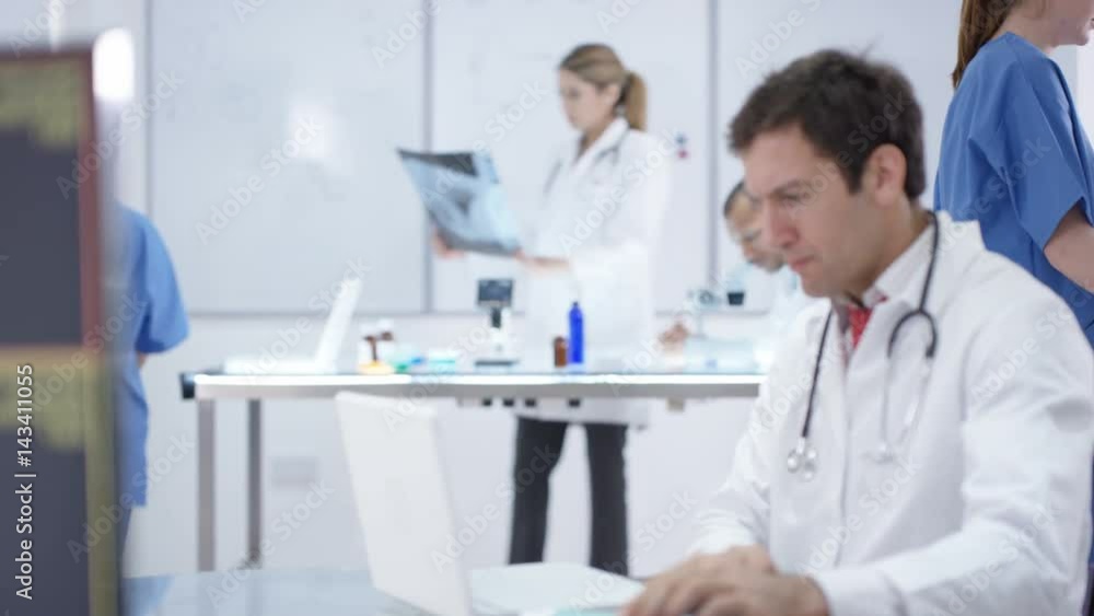 Medical team working together, using technology & looking at x-rays Medical team working together, using technology & looking at x-rays