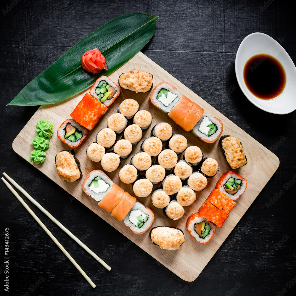 Japanese food. Sushi rolls, sauce and chopsticks on a black background. Top view. Flat lay