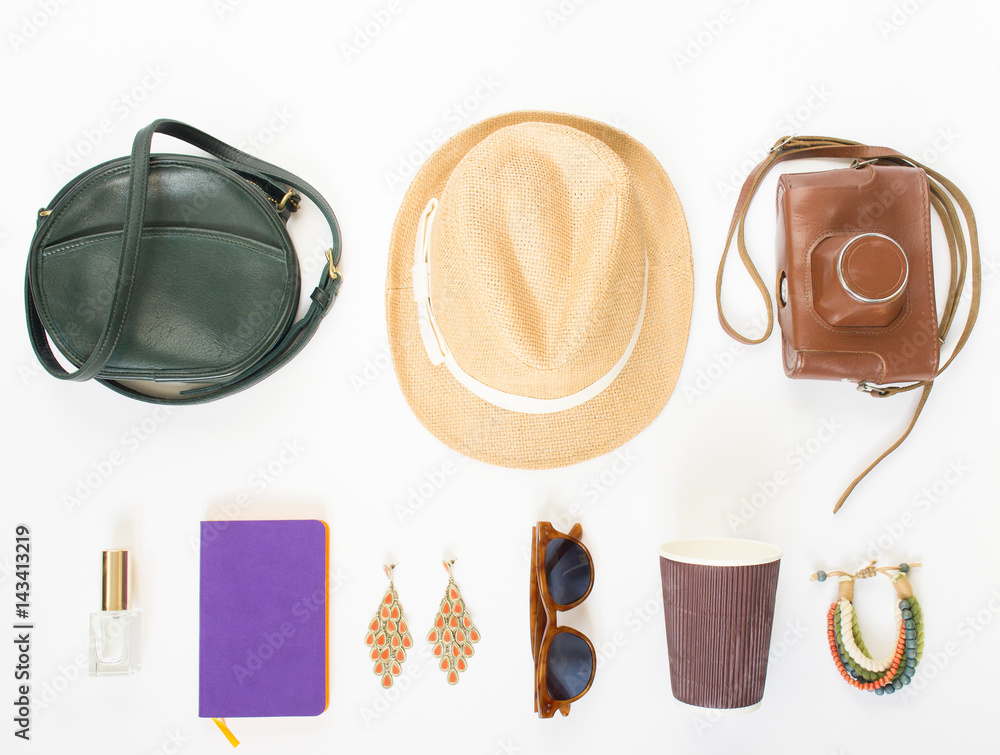 Holiday/travel background. Green cross bag, straw hat, retro brown sunglasses, retro camera, hippie bracelet and earrings, violet noutbook, coffee cup. Flat lay, top view.
