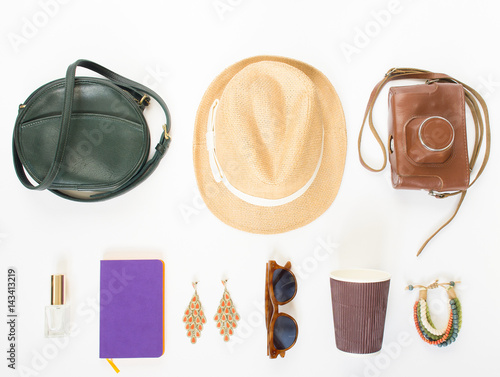 Holiday/travel background. Green cross bag, straw hat, retro brown sunglasses, retro camera, hippie bracelet and earrings, violet noutbook, coffee cup. Flat lay, top view. photo