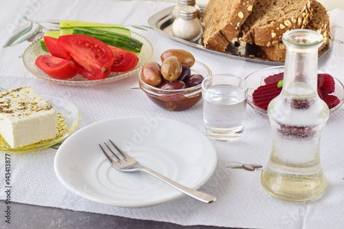 Greek food, mezedes. Jars with olive oil and vine vinegar, olives,feta, tzatziki, dark bread, raki, beetroot, fresh cucumber and tomato on a white background. Healthy eating concept. Healthy food.