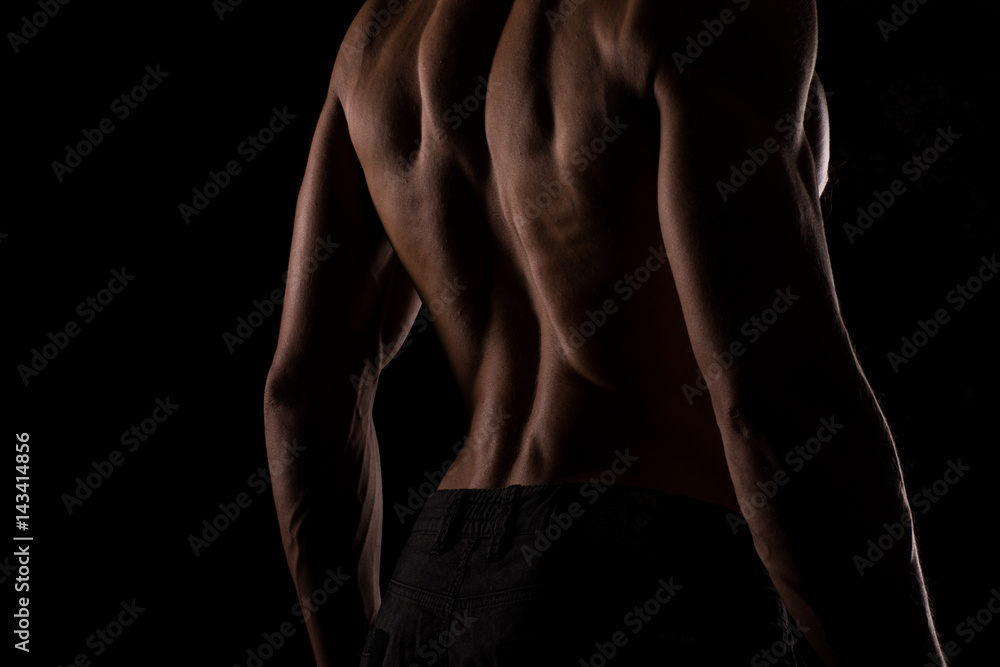 Fototapeta premium Mężczyzna fitness model, kulturysta poza plecami na czarnym tle