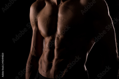 Muscular and defined six pack abs on handsome male model posing on black background