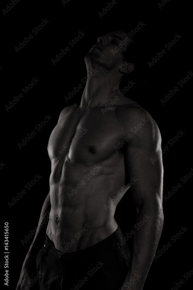 Muscular and defined six pack abs on handsome male model posing on black background