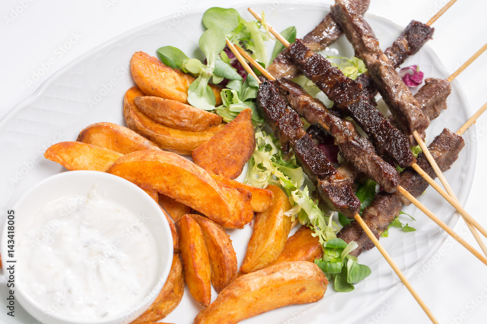 Lamb skewers on salad with wedges potatoes