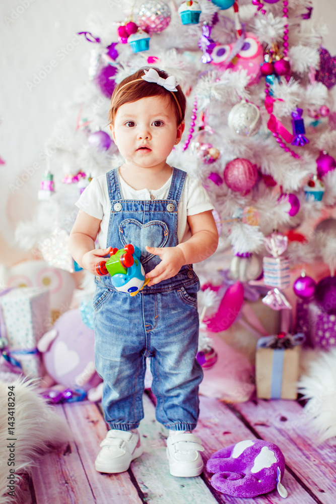 Girl in jumpers stands with toy before Christmas tree Girl in jumpers stands with toy before Christmas tree