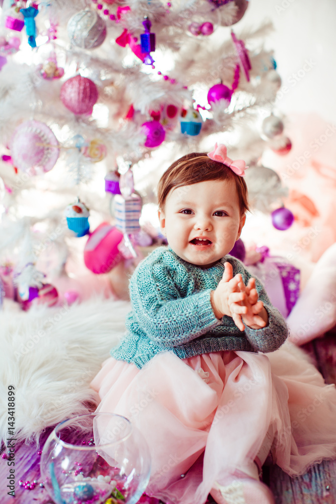 Pretty little child sits on fluffy carpet before Christmas tree Pretty little child sits on fluffy carpet before Christmas tree