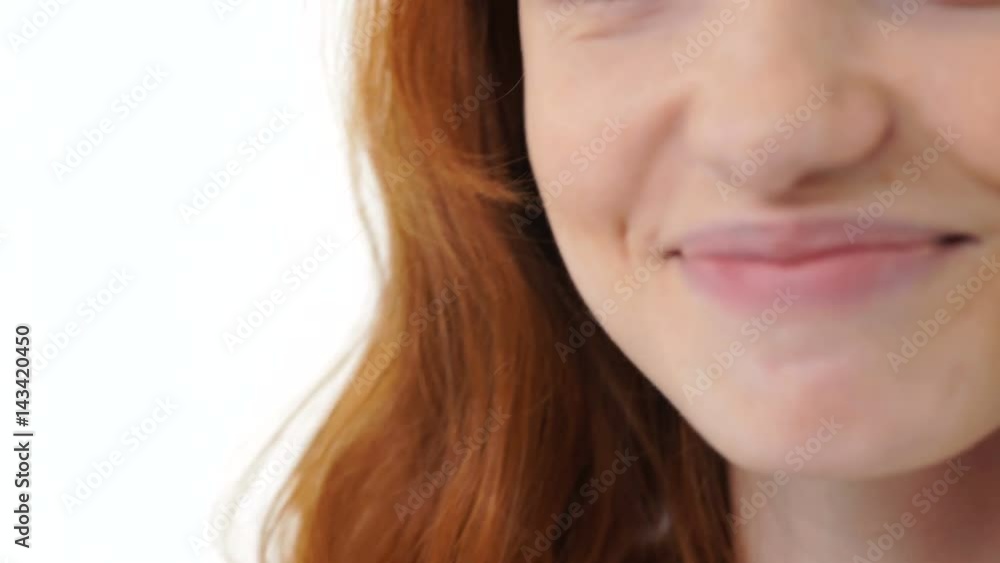 Close up of a young attractive sensual woman with red hair smiling and looking at camera isolated over white Close up of a young attractive sensual woman with red hair smiling and looking at camera isolated over white