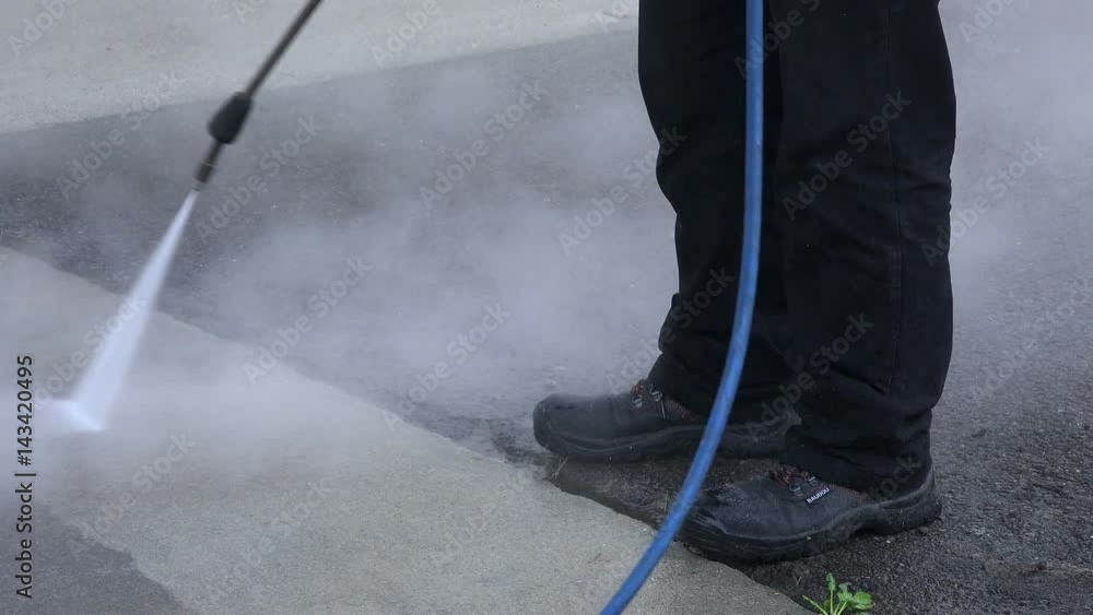 Person washing the floor with a high pressure washing machine. Person washing the floor with a high pressure washing machine.
