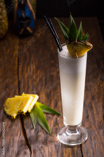 Ping Kolad's cocktail with rum, pineapple juice, coconut syrup with a pineapple piece in a high glass photo