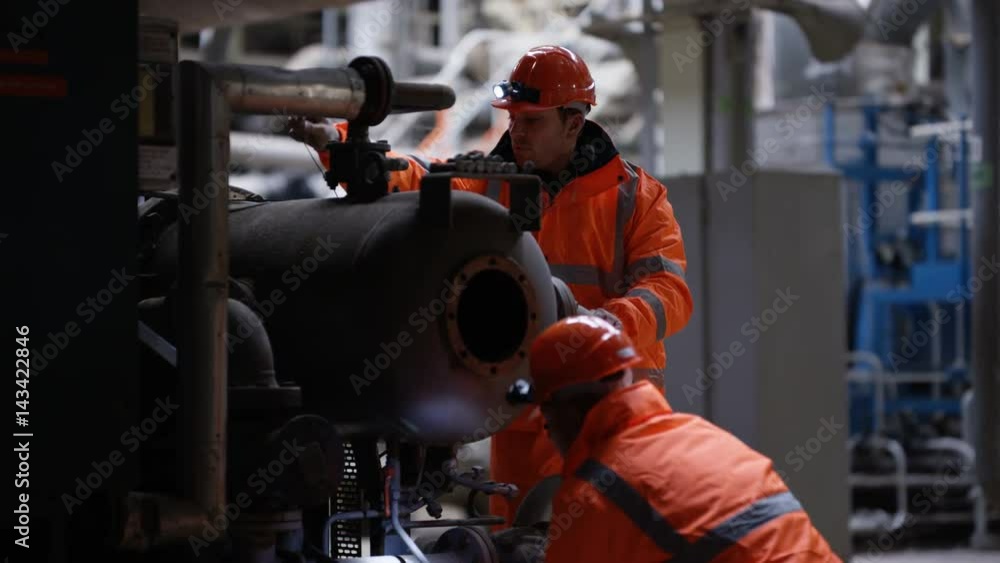 Engineering team carrying out maintenance in power plant with foreman watching