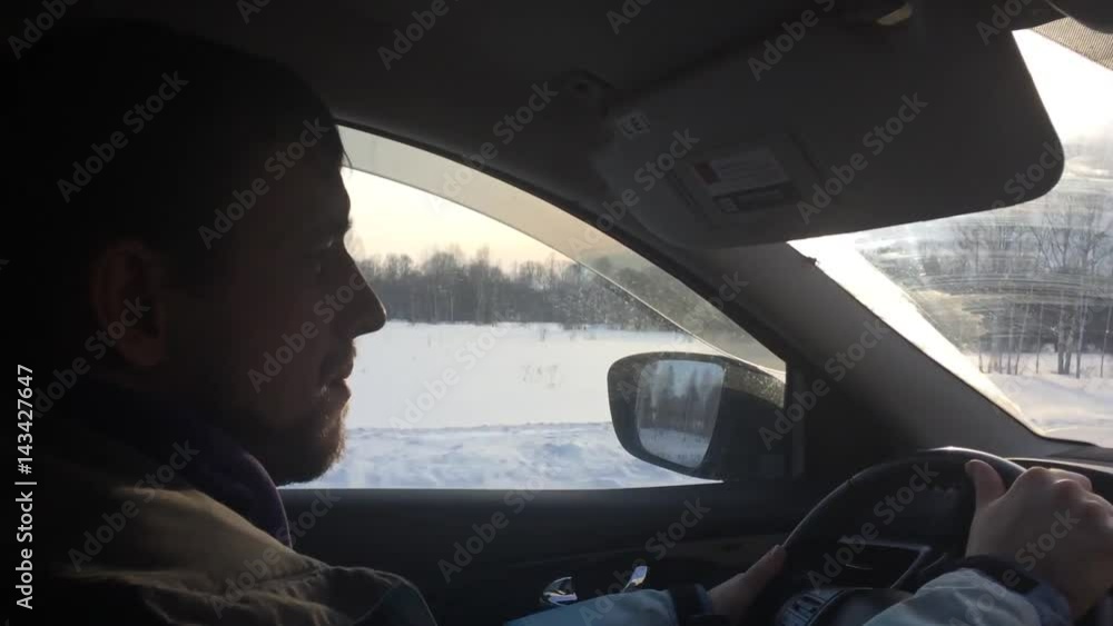 A young serious man is driving a car, on a winter road in the rays and glare of sunset.1 920x1080 A young serious man is driving a car, on a winter road in the rays and glare of sunset.1 920x1080