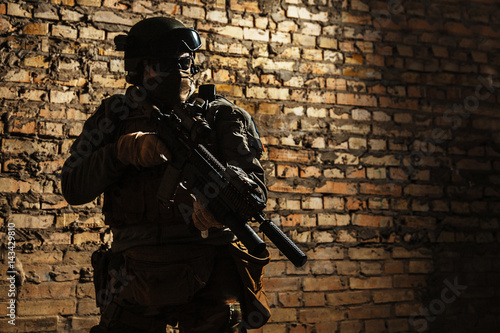 Special forces operator pointing weapon in the dark. Combat helmet, and bulletproof vest are on. Low key image, shadow soldier