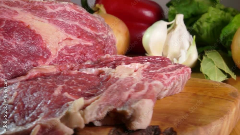 Raw beef steak cut on a wooden board, slow motion Raw beef steak cut on a wooden board, slow motion