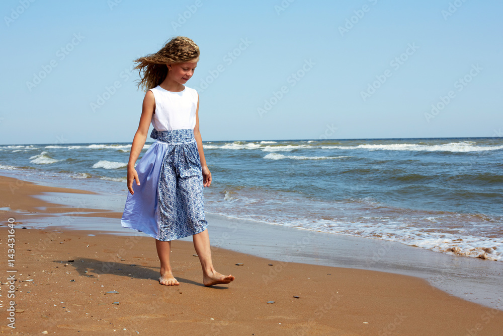 Happy child walks along the coastline ocean