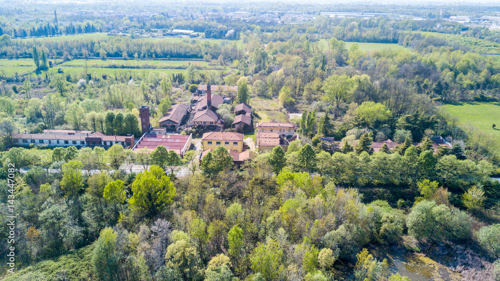 Obraz premium Natura e paesaggio: vista aerea di una fornace e ciminiera, bosco e di laghi, verde ed alberi. Parco delle Groane, Mombello (Laghettone), Limbiate, Milano, Italia