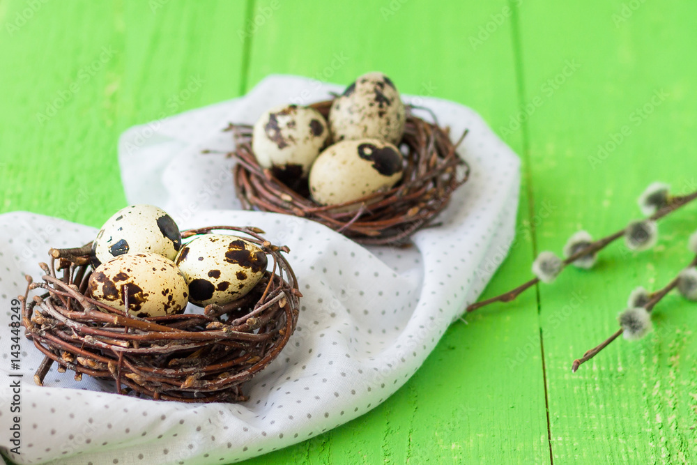 Easter quail eggs in nests. Green wooden table. Pussy-willow in a vase Easter quail eggs in nests. Green wooden table. Pussy-willow in a vase
