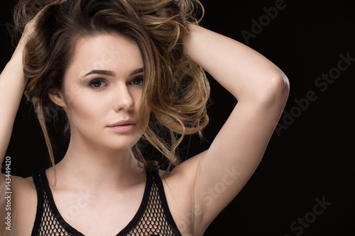 Ready to rock your world. Shot of a stunning sexy beautiful young woman posing gracefully holding her hair looking to the camera seductively on black background