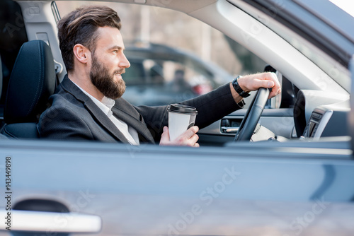 Handsome businessman driving a car with coffee to go in the city © rh2010