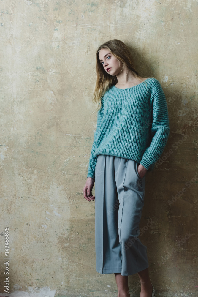 Pretty young girl with blond hair in fashionable sweater, culottes