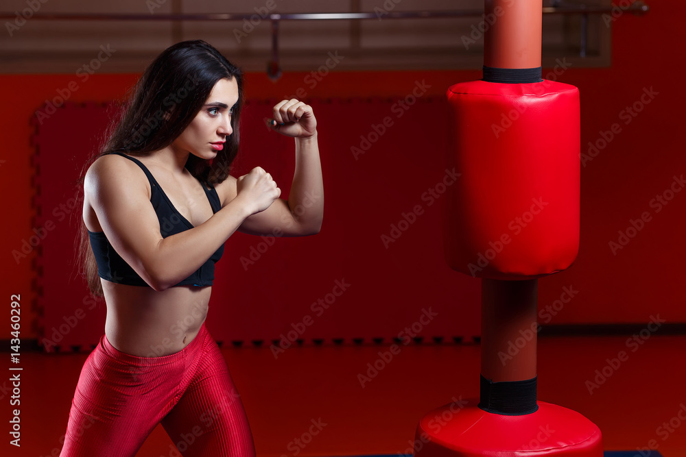 Woman boxing, hitting a punching dummy