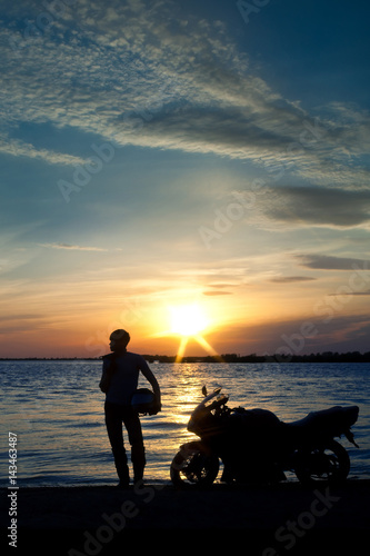 Silhouette of man and a motorcycle with sunset background © Евгений Степаненко