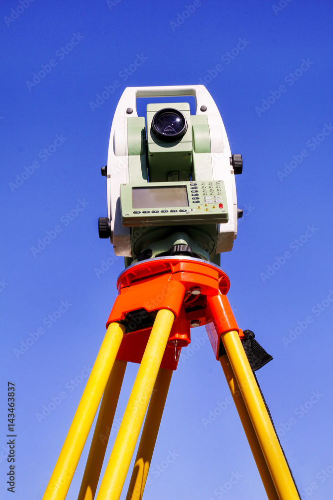 Total station with blue sky in the background. Survey Instrument geodetic  device, total station set in the field. Total station surveying and  measuring engineering equipment at work in garden. Stock-Foto | Adobe