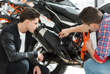 Advice needed. Shot of a motorcycle salon manager showing a new motorbike to his customer