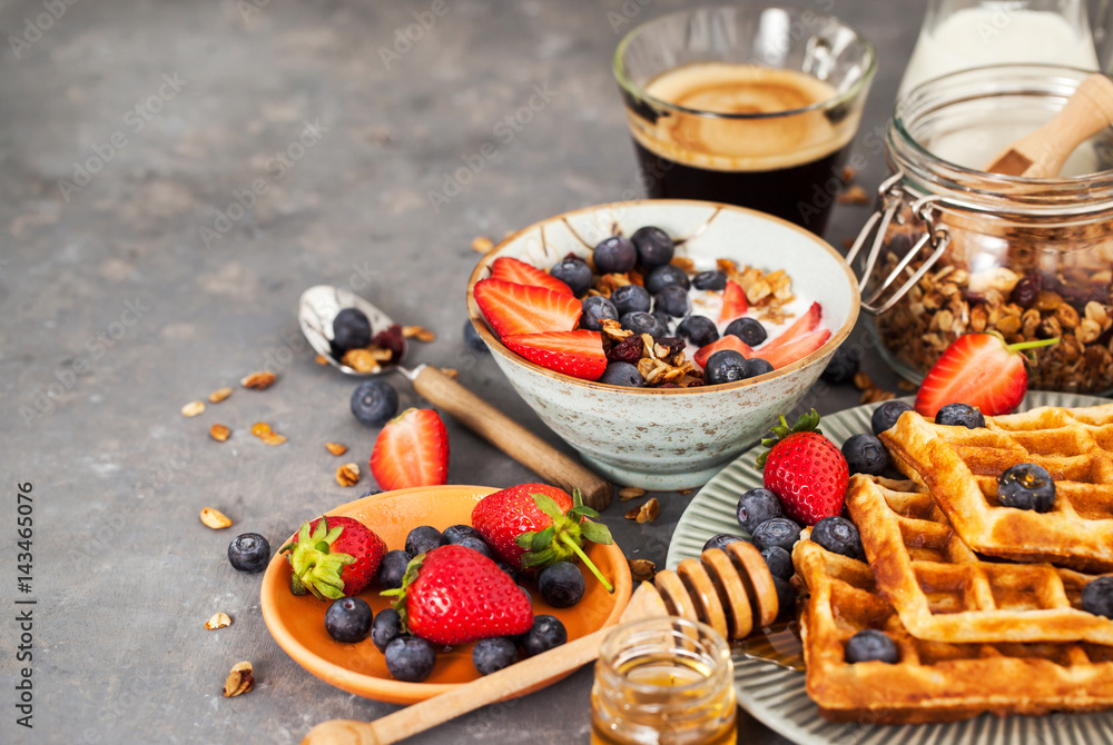 Breakfast table with cereal granola, milk, fresh berries, coffee and waffles Breakfast table with cereal granola, milk, fresh berries, coffee and waffles