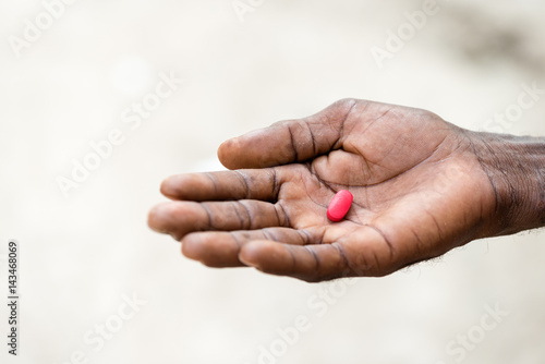 African black man's hand taking a red pill.Unrecognizable person