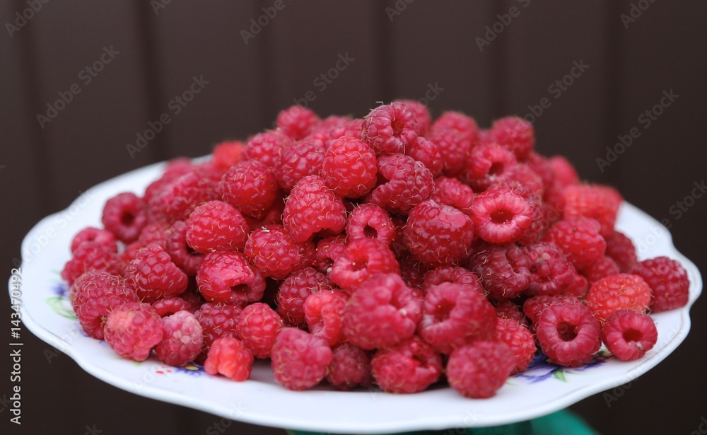 Red fresh ruspberry on the plate in the garden in the summer Red fresh ruspberry on the plate in the garden in the summer