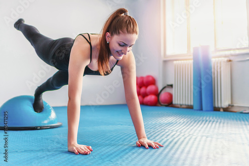 Woman doing pilates exercises with bosu balance trainer