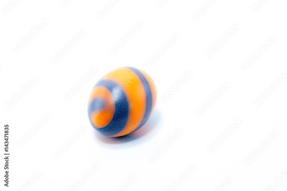 Easter egg hand painted in home - orange with blue stripes, isolated in white background
