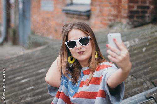 A hippest girl in an old courtyard with a phone makes a selfie photo