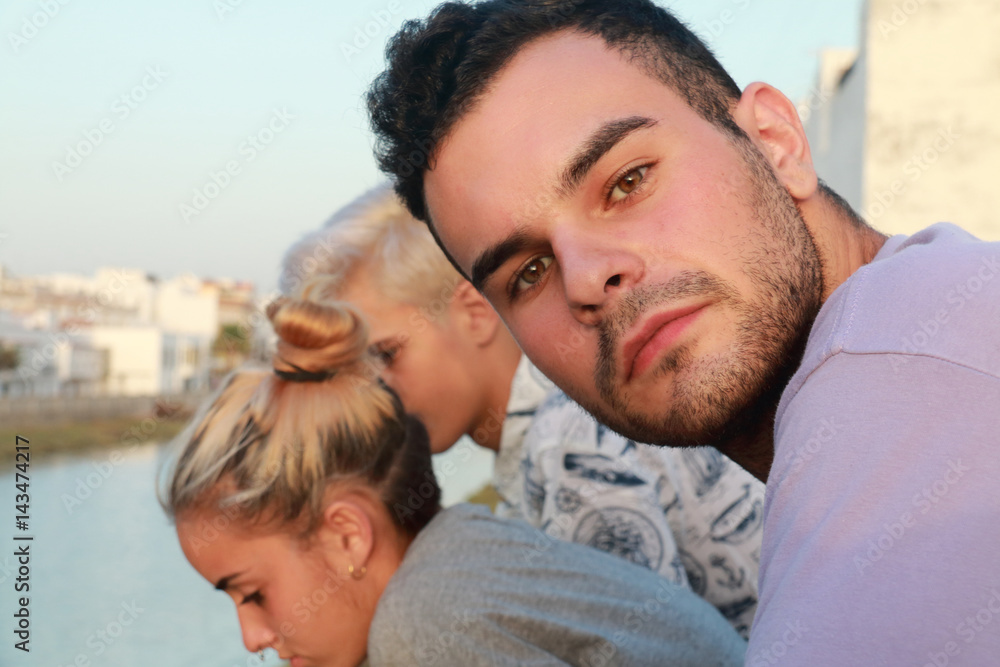 Handsome guy looking at the camera and in the background a boy and a girl Handsome guy looking at the camera and in the background a boy and a girl