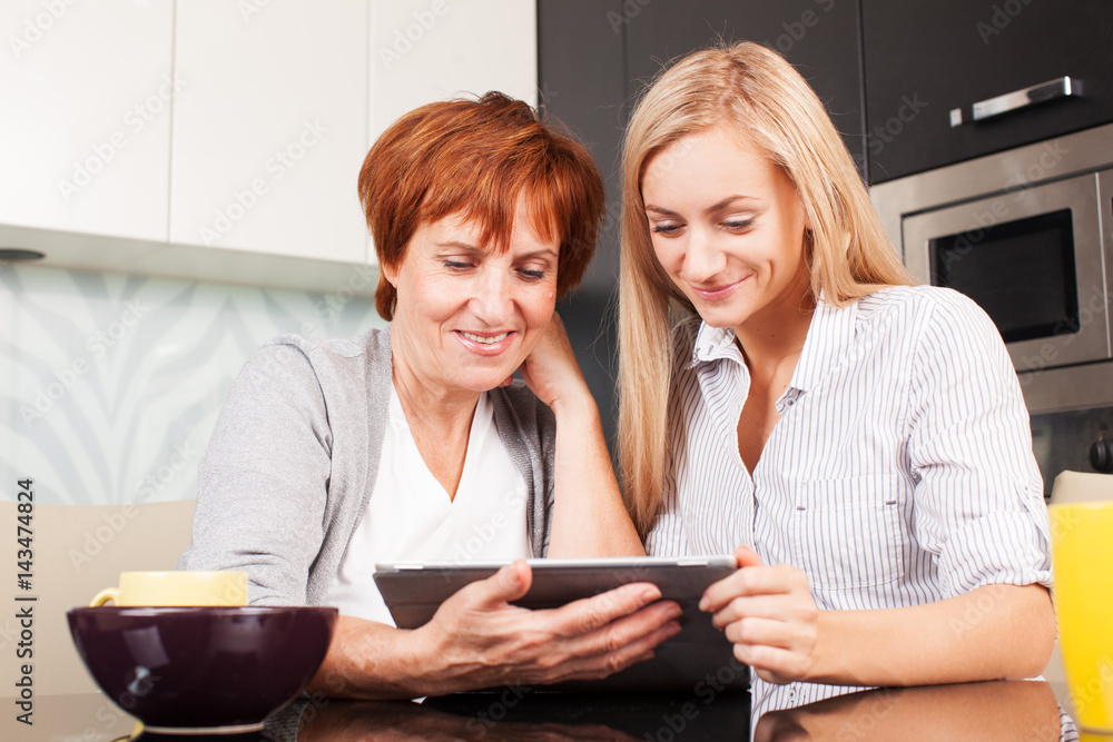 Mother and daughter looking in tablet pc Mother and daughter looking in tablet pc