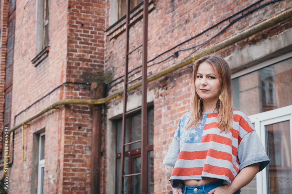 A hipster girl in an old courtyard posing and smiling A hipster girl in an old courtyard posing and smiling