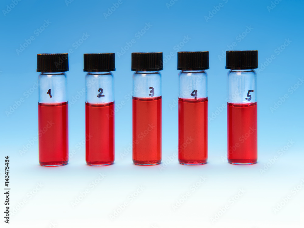 Red liquid samples in a transparent plastic tray on blue Red liquid samples in a transparent plastic tray on blue
