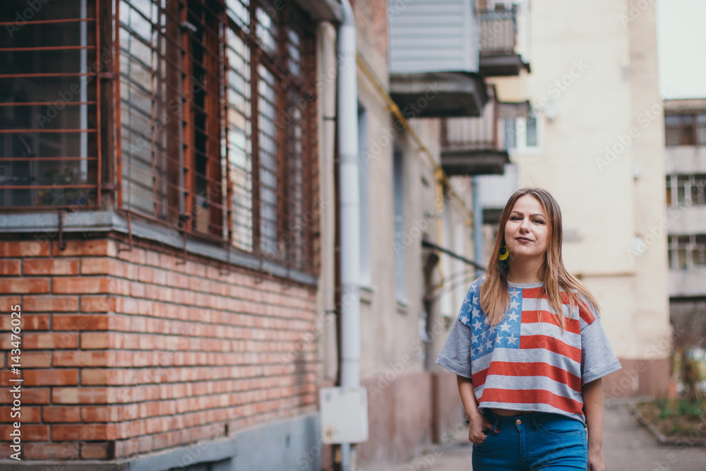 A hipster girl in an old courtyard posing and smiling A hipster girl in an old courtyard posing and smiling